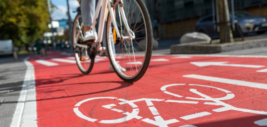 woman cycling along red bike lane road in city