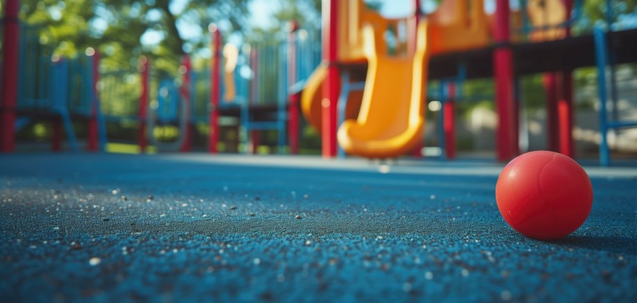 A red ball on a blue playground surface with play equipment