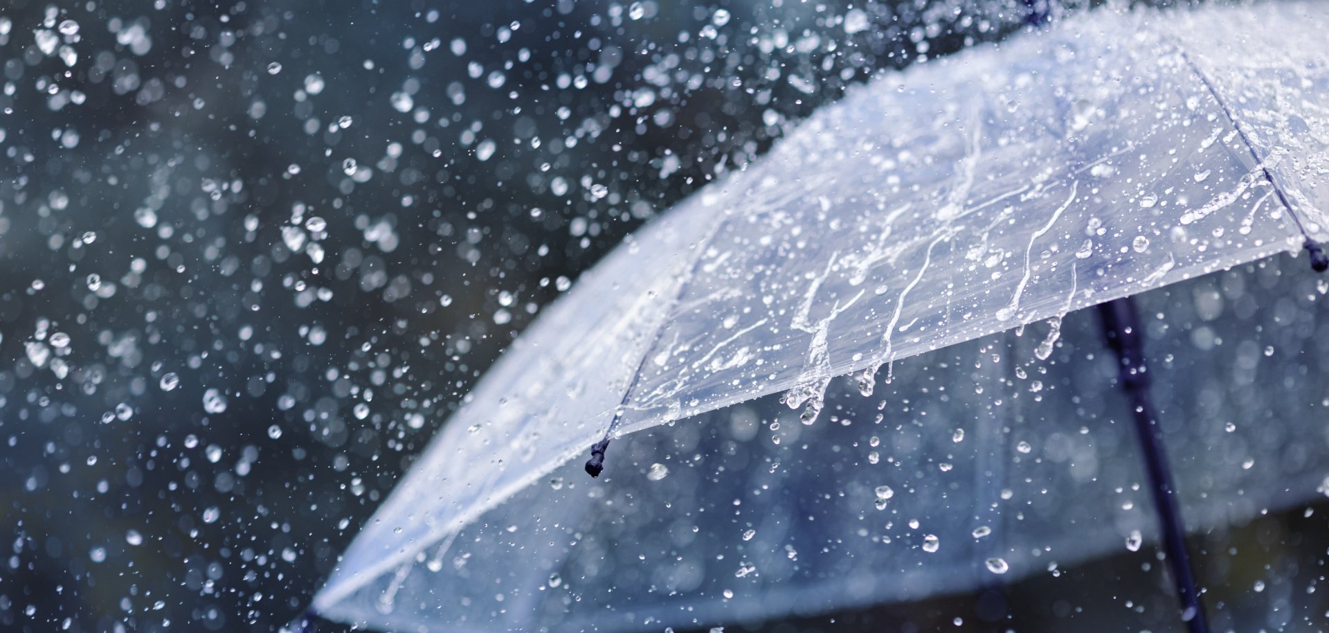 Transparent umbrella under heavy rain against water drops splash