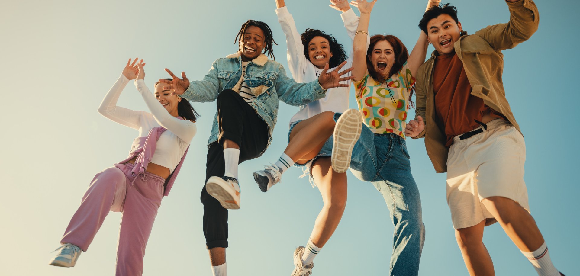 Group of friends jumping and having fun outdoors in the sunshine