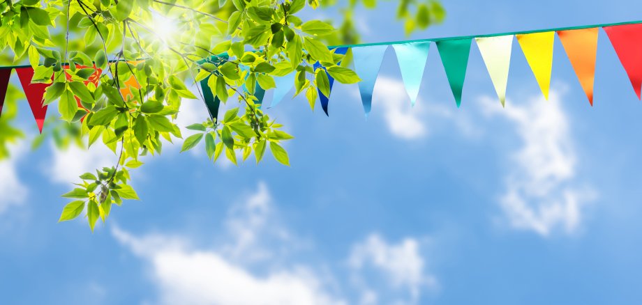 colorful pennant string decoration in green tree foliage on blue
