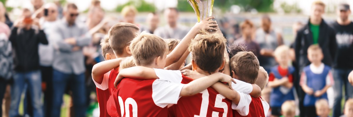 Happy children winning sports tournament. Kids in sports teams win trophies on tournaments Schoolboys standing in a circle and holding the golden trophy. Victory celebration of a youth sports team